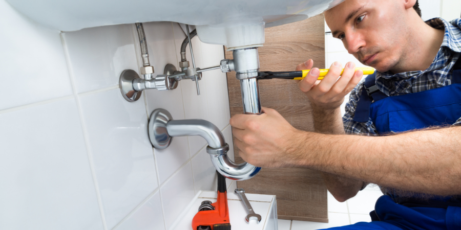 Plumber fixing sink pipes in a bathroom